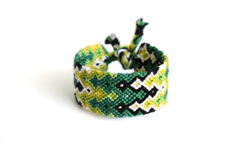 Selective focus of multi-colored woven DIY friendship bracelet handmade of embroidery bright thread with knots isolated on white background. Gradient pattern