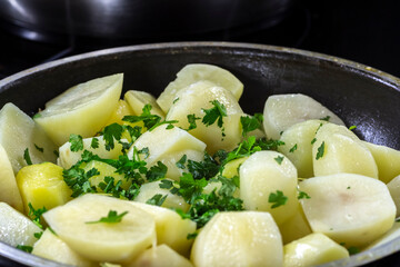 Close-up of potatoes with herbs in a pan during frying.