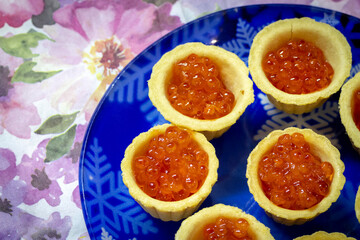 Naklejka na ściany i meble Red caviar in waffle cups on the table close-up.
