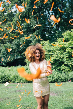 Girl with big afro playing with confetti in the park