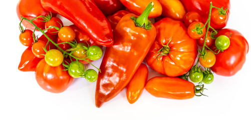 Harvest of fresh red and green tomatoes, and red peppers from above on the white table