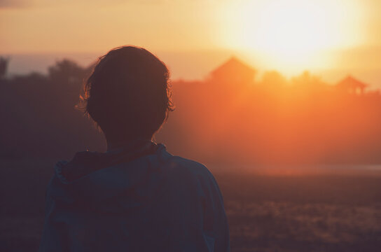 Silhouette portrait of a young woman with short hair watching beautiful sunset