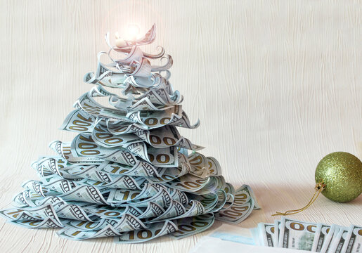  Christmas tree made of paper dollar bills on a white background with a green Christmas ball and banknotes,-the concept of wishes for financial well-being and fulfillment of wishes