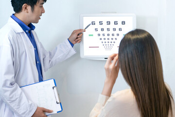 Fototapeta na wymiar Optometrists point to vision charts to examine the eyesight of Asian women patients, in ophthalmology clinic, selective focus