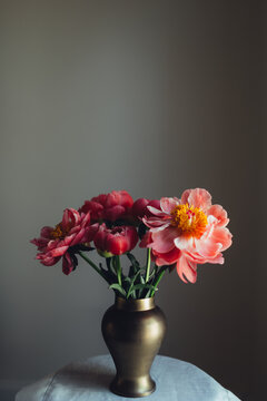 A bouquet of pink colored peonies in a brass vase