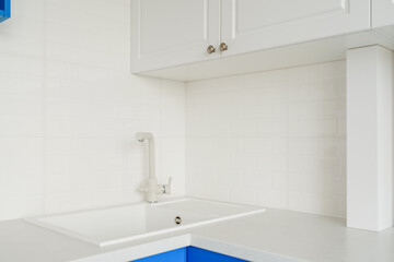Fototapeta na wymiar A modern bright kitchen with white and blue wardrobe.
