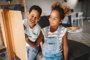Cute children girl and boy painting together. Education, art, fun and creativity concept.