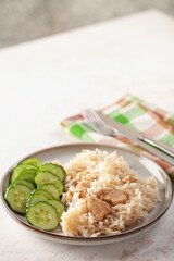 Rice with chicken and cucumbers in a plate on the table.