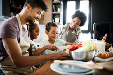 Happy african american family preparing healthy food together in kitchen