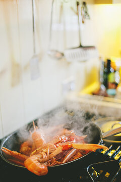 Steam coming up from simmering scampi pan on the stove