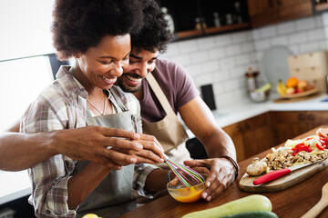 Happy young couple cooking together in the kitchen at home.