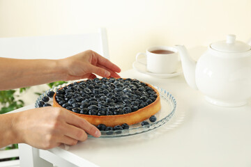 Fototapeta na wymiar Woman hands hold tasty blueberry pie on white table