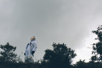 Person in spacesuit looking up at the sky.