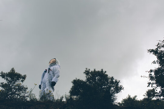 Person in spacesuit looking up at the sky.