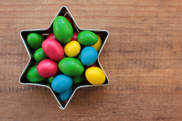 Colorful jelly beans candies in a star-shaped cooking cutter on wooden background. Sweet holiday...