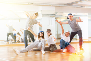 Fototapeta na wymiar Positive teen girls and boys posing in dance studio during hip hop class