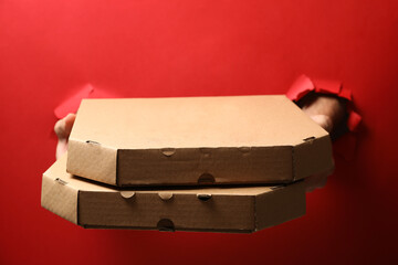Hands hold boxes with tasty pizza on red background