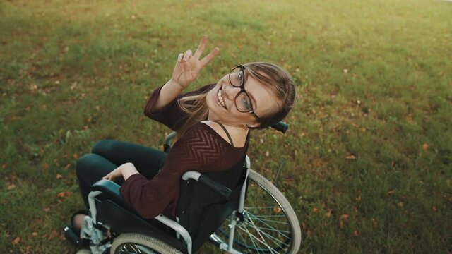 Young caucasian disabled brunette woman looking overshoulder with peace fingers gesture. High quality 4k footage