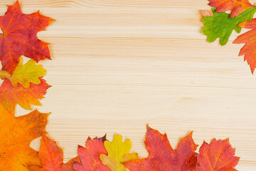 Naklejka na ściany i meble frame composed of autumn leaves on wooden background