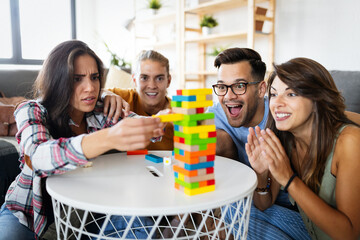 Group of young happy friends having fun playing wood board game