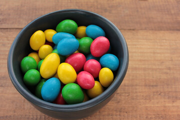Fototapeta na wymiar Colorful jelly beans candies in a bowl on wooden background. Sweet holiday treats for kids