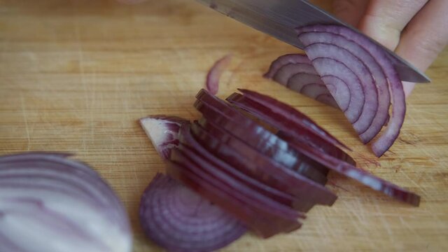 Slice onion on the cut board. A view of a woman hand's cutting slice an onion on the cut board.