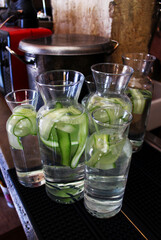 Decanters of refreshing cool water with cucumber and lemon in the bar at the entrance. Refreshing water with cucumber in tall glass decanters..