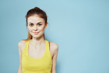 Sportive woman yellow tank top pigtail towards fitness blue background