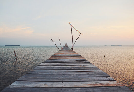 Long, empty and old wooden dock over the water at sunset
