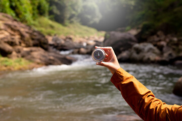 Hands traveler solo woman holding compass at waterfall,Navigation for travel © gballgiggs