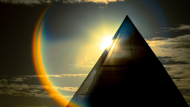 Sunrise sunset behind pyramid with rainbow lens flare