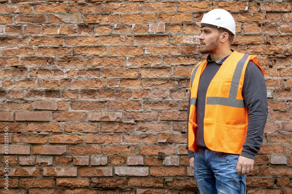 Wall mural builder in a hard hat on a brick wall background.