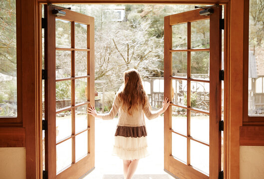 Woman walking through wood doors to the outside