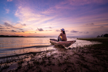 Naklejka na ściany i meble Woman tourist sitting on boat at the Sirindhorn Dam at Pattaya Noi (Little Pattaya) beach in Ubon Ratchathani.