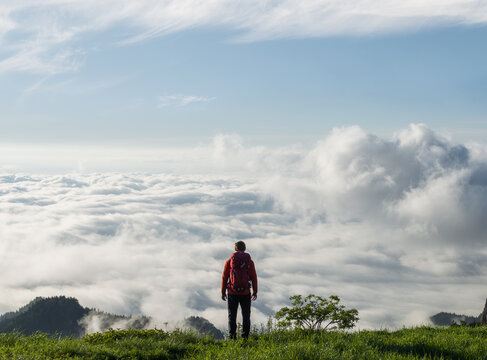 Hiker on top of mountain admiring the sea of clouds