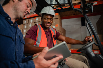 Caucasian worker holding digital tablet showing ethnic worker location of parcel driving forklift in warehouse