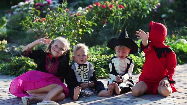 Group of little and toddlers in witch costumes, skeleton and executioner for halloween children is holiday waving hand looking at the camera