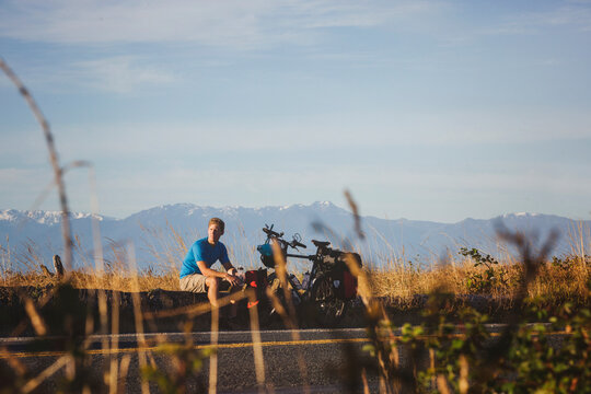 Young, fit man resting from bicycle touring expedition at sunrise