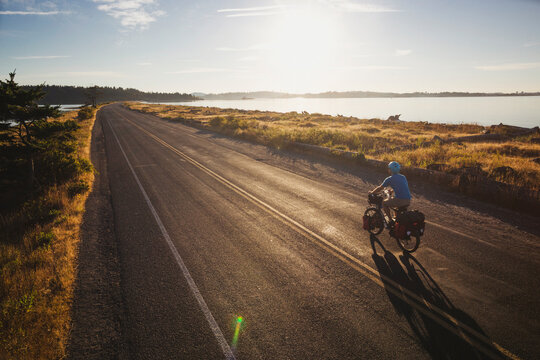 Young, fit man on bicycle touring expedition at sunrise