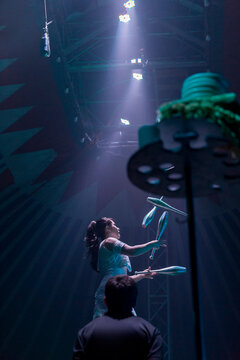 Circus performer on a unicycle juggling multiple batons