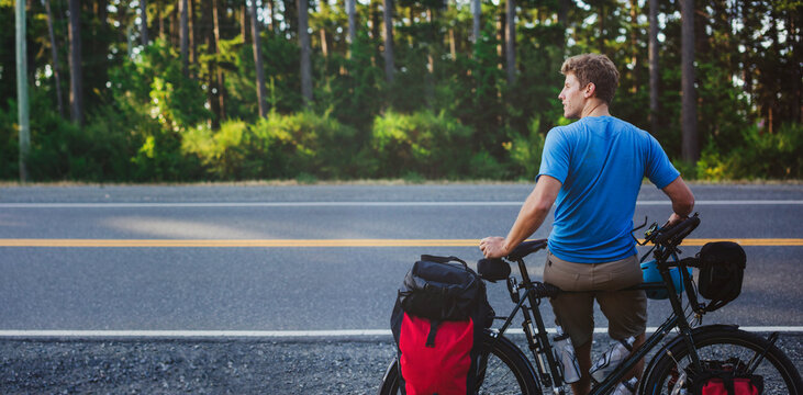 Young, fit man resting from bicycle touring expedition at sunrise