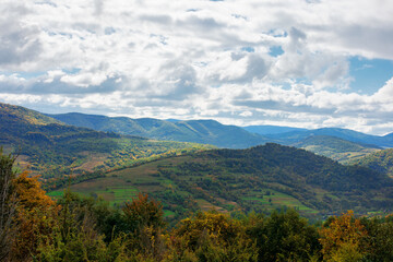 mountainous countryside in autumn. beautiful nature on a sunny day. dry grass on the meadow. ridge in the distance. clouds on the sky