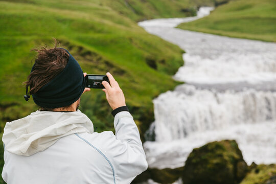 Tourist Taking a Photo of an Islandic Waterfall