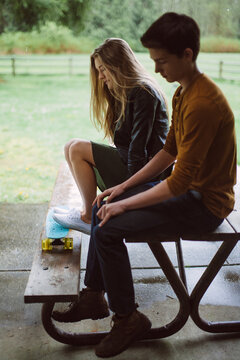 Boy and Girl Sitting on a Picnic Bench out of the Rain
