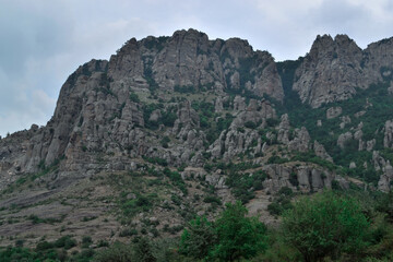 High rock pillars in Valley of Ghosts of the mountain range Demerji, Crimea. Green bushes in the foreground. Unique place on Earth