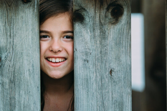 Smilling Girl Peeking Through A Fence