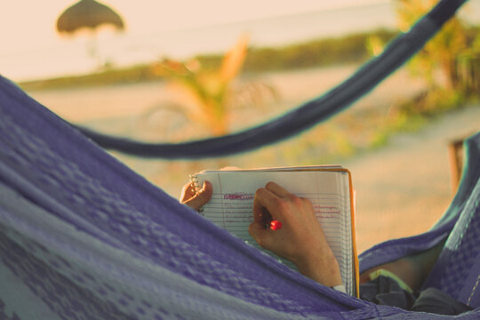 Vacationer in hammock writing in diary