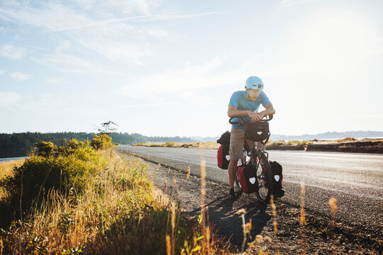 Young, fit man resting from bicycle touring expedition at sunrise
