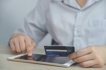 Businessman hand hold credit card to online shopping on tablet from home, payment e-commerce, internet banking, spending money for next holidays