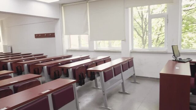 Dolly shot slowly walking into the empty university classroom with wooden desks